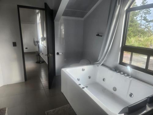 une salle de bain blanche avec une baignoire et une fenêtre dans l'établissement Villa Cotopaxi, Cerro Azul, à Los Altos de Cerro Azul