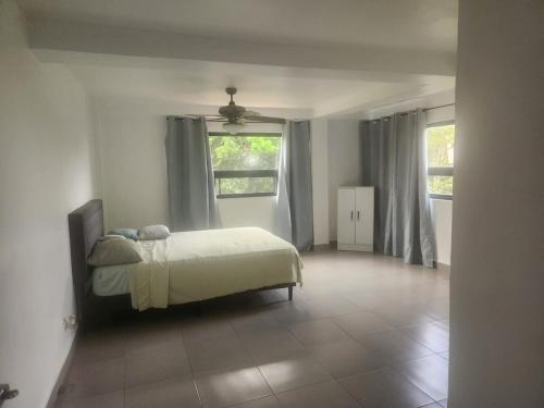 une chambre avec un lit et deux fenêtres dans l'établissement Villa Cotopaxi, Cerro Azul, à Los Altos de Cerro Azul