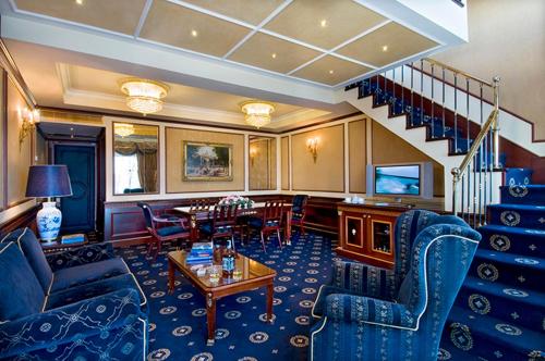 a living room with blue furniture and a staircase at Grand Hotel Bristol in Stresa