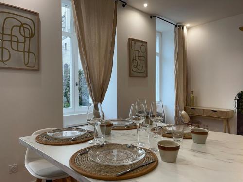 einen Tisch mit Tellern und Weingläsern darauf in der Unterkunft Henri IV in Pau