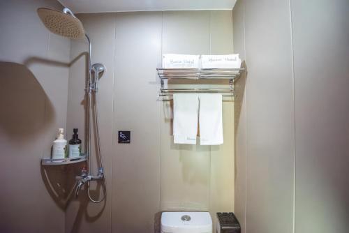 a bathroom with a shower and a toilet with towels at 一间森林酒店上海外滩人民广场地铁站店 in Shanghai