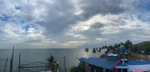 a view of a beach with palm trees and the ocean at Rainbow Beach Mũi Né - Homestay & Coffee in Ấp Khánh Phước (1)
