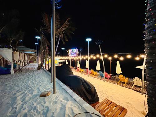 a beach with umbrellas and chairs in the sand at night at Rainbow Beach Mũi Né - Homestay & Coffee in Ấp Khánh Phước (1)