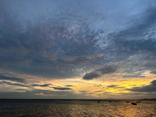 a cloudy sky over the water with boats in it at Rainbow Beach Mũi Né - Homestay & Coffee in Ấp Khánh Phước (1)