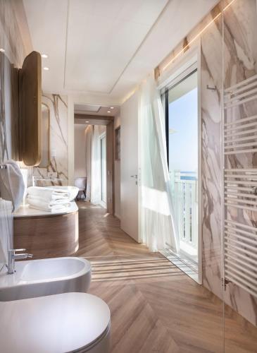 a bathroom with a toilet and a sink and a window at Hotel Corallo in Riccione