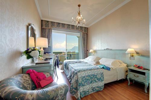 a hotel room with a bed and a chair at Grand Hotel Bristol in Stresa