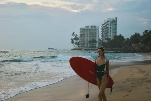 a woman in a bikini holding a surfboard on the beach at Radisson Collection Resort Galle in Galle