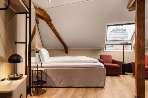 a bedroom with a bed and a red chair at Scandic Holberg in Oslo