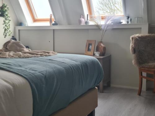a bedroom with a bed with a blue blanket on it at B&B de Keinsmer in 't Zand