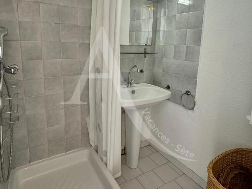 une salle de bain avec un lavabo, une douche et une baignoire dans l'établissement Studio avec balcon et parking a 2 pas des plages, à Sète