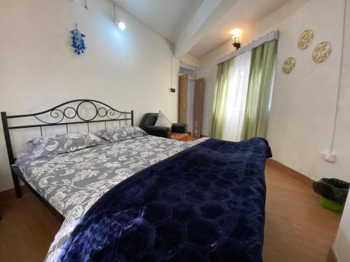a bedroom with a bed with a blue comforter at Rubysang in Darjeeling