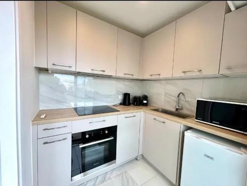 une petite cuisine avec des armoires blanches et un micro-ondes dans l'établissement Studio moderne à Juan les Pins - 30 m² avec balcon, à Juan-les-Pins