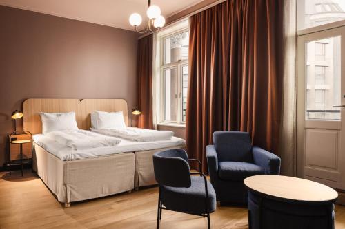 a bedroom with a bed and two chairs and a table at Scandic Holberg in Oslo