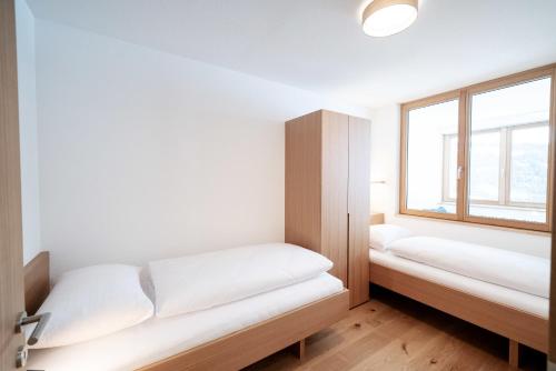 a room with two beds and a window at Berg Aparts Faschina - 08 in Fontanella