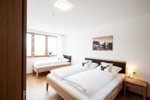 a white bedroom with two beds and a couch at Berg Aparts Faschina - 02 in Fontanella