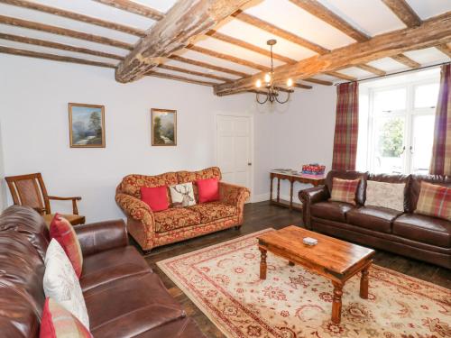 a living room with leather couches and a coffee table at Lea Farm House in Kidderminster