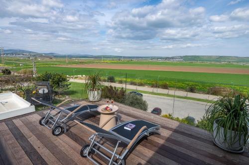 a deck with two chairs and a view of a field at נעם בגלבוע -2 סוויטות מהממות עם נוף לגלבוע in H̱efẕi Bah