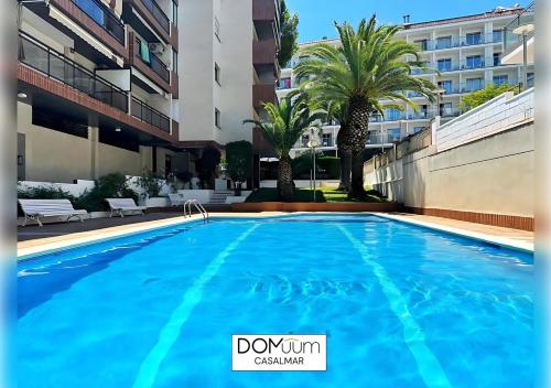 a swimming pool in front of a building with palm trees at DOMuum Holidays -CASALMAR Family Home in Salou