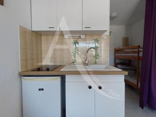 une cuisine avec des armoires blanches et un évier dans l'établissement Studio avec terrasse a 2 min des plages a pied, à Sète