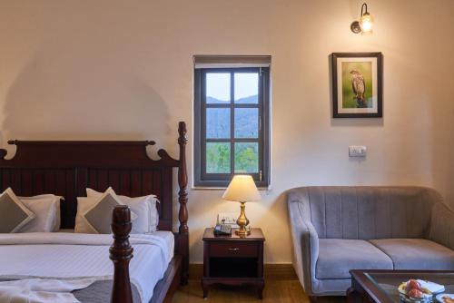 a bedroom with a bed and a couch and a window at The Hunting Lodge - Luxury Resort in Udaipur in Udaipur