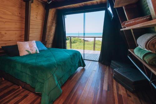 a bedroom with a bed and a large window at Chalé Beira Mar Com Banheira com Vista in Itapoa