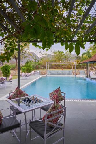 a chess board on a table in front of a pool at The Hunting Lodge - Luxury Resort in Udaipur in Udaipur