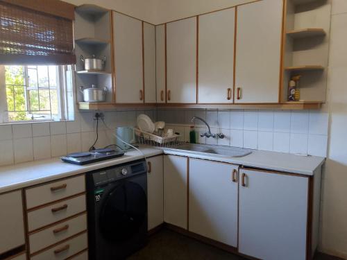 a kitchen with white cabinets and a black dishwasher at Duminy Guest Lodge in Bellville