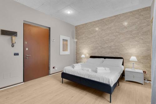 a bedroom with a large bed and a stone wall at The house of via muratori 11 in Milan