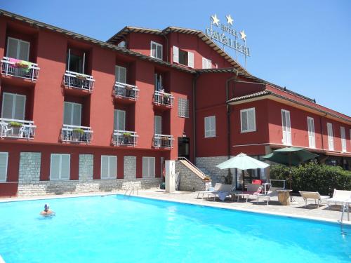 a person in a swimming pool in front of a hotel at Hotel Cavalieri in Passignano sul Trasimeno