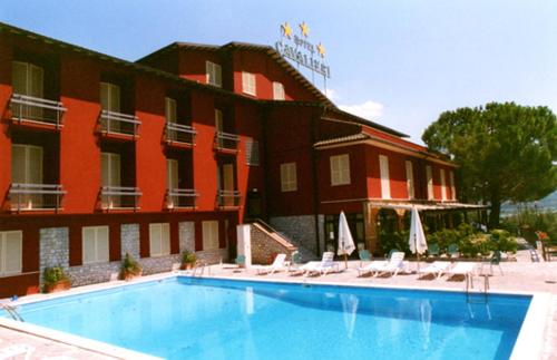 a hotel with a swimming pool in front of a building at Hotel Cavalieri in Passignano sul Trasimeno