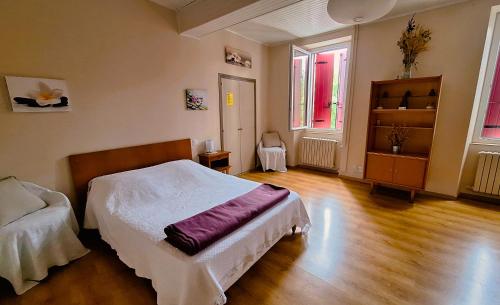a bedroom with a bed and a wooden floor at La Maison du Soleil in Saint-Gaudéric