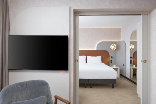 a hotel room with a bed and a flat screen tv at Mercure London Earls Court in London