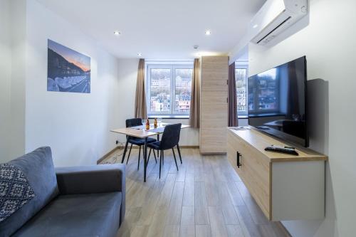 a living room with a couch and a table with a television at NOMAD APARTMENTS - Côté Meuse in Dinant