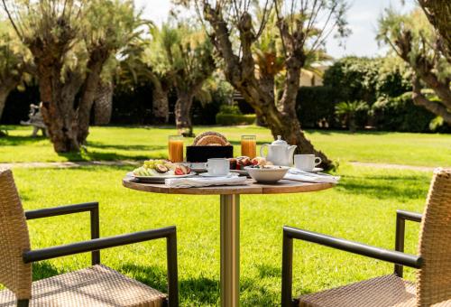 un tavolo con del cibo sopra in un cortile con due sedie di Plaza Resort ad Anávissos