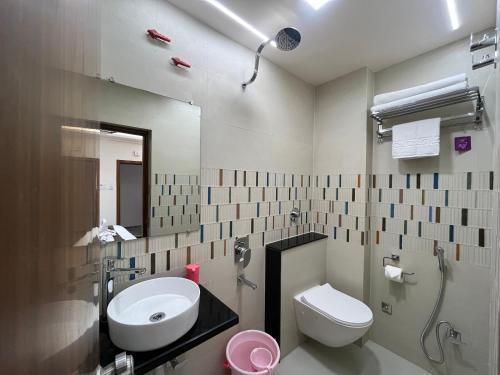 a bathroom with a sink and a toilet and a mirror at Aaditri Inn in Gorakhpur
