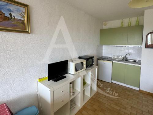 une cuisine avec un four micro-ondes sur un comptoir blanc dans l'établissement Studio cabine avec parking proche de la mer, à Sète