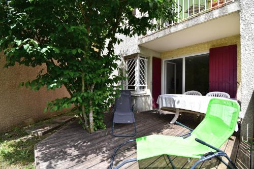 a green chair and a table on a deck at Escapade Provençale - T2 avec cuisine et terrase privée in Digne-les-Bains