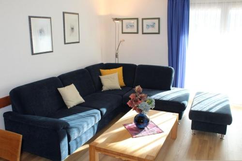 Ferienhaus Nr 121, Kategorie Komfort, Feriendorf Hochbergle, Allgäu في Karlsebene: أريكة زرقاء في غرفة المعيشة مع طاولة