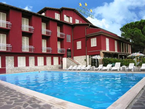 a hotel with a pool in front of a red building at Hotel Cavalieri in Passignano sul Trasimeno