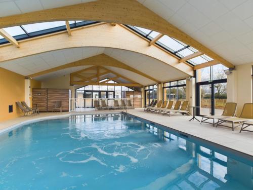 une grande piscine avec des fenêtres et des chaises dans l'établissement Joli chalet pour 6, piscine chauffée à l'année, à Saint-Gilles-Croix-de-Vie