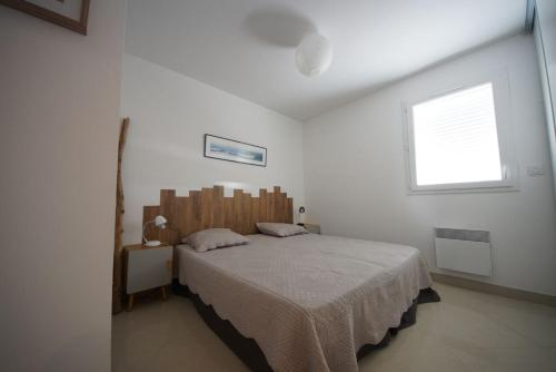 une chambre avec un grand lit dans une pièce blanche dans l'établissement T3 tout confort à 100m de la plage, Parking couvert gratuit, à Saint Pierre La Mer