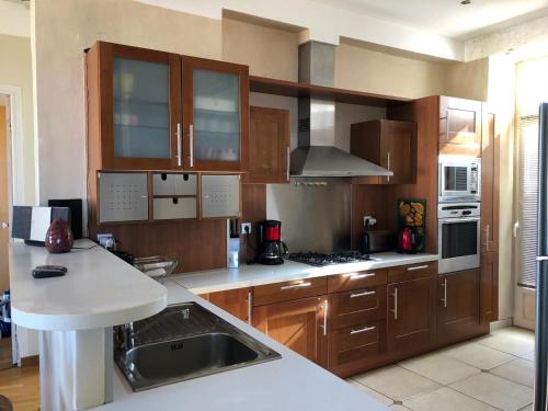 une cuisine avec des placards en bois et des comptoirs blancs dans l'établissement Appartement Blasini Proche plage & ville, à LʼÎle-Rousse