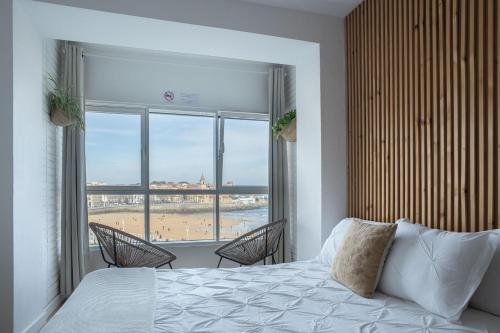 a bedroom with a bed and a view of the beach at Boogalow Hostel in Gijón