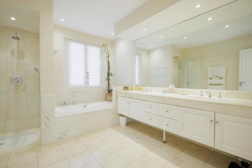 une salle de bain avec deux lavabos, une baignoire et une douche dans l'établissement Domaine Picasso, à La Colle-sur-Loup