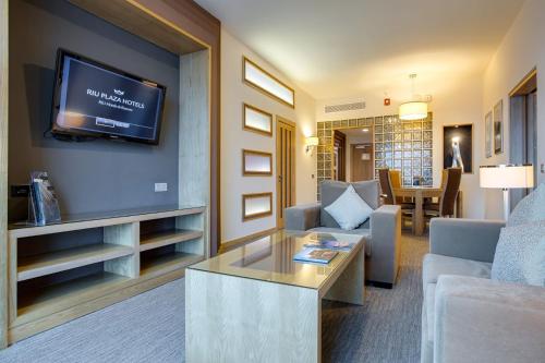 a living room with a couch and a tv on a wall at Riu Plaza Panamá in Panama City