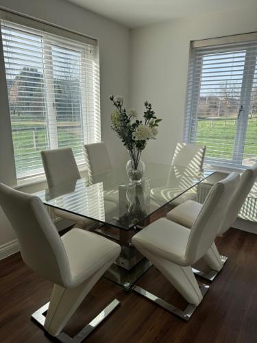 a dining room with a glass table and white chairs at Modern & Spacious 3-Bedroom Home in Dartford, Ideal for Families, Groups and Contractors in Dartford