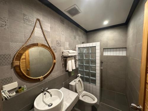 a bathroom with a sink and a toilet and a mirror at โรงแรมชาวเกาะพีพี Chaokoh Phi Phi Island in Phi Phi Don