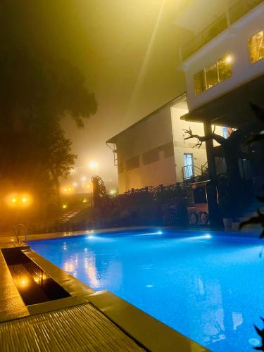a swimming pool in front of a building at night at Skylark Holidays Premium in Chinnakanal