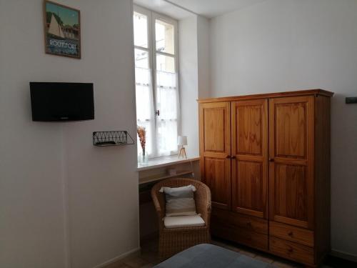 Cette chambre dispose d'une télévision, d'une chaise et d'une fenêtre. dans l'établissement Espoumet, à Rochefort