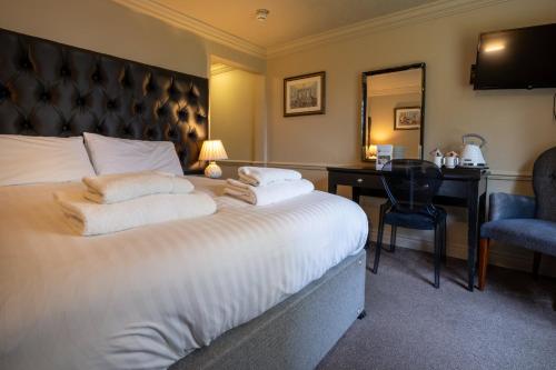 a hotel room with a large bed and a desk at Hollin House Hotel in Macclesfield